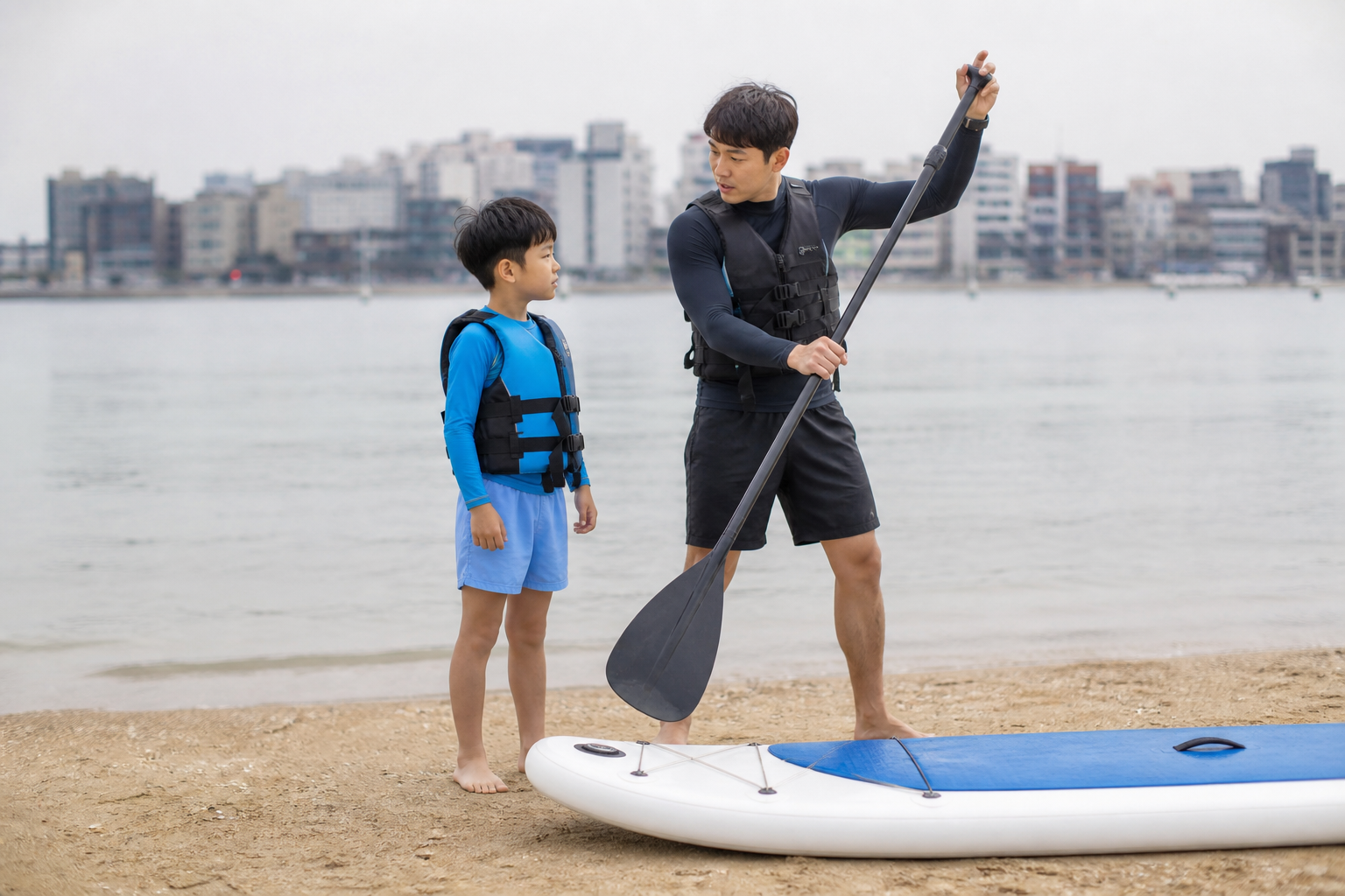 광안리 해변에서 구명조끼를 입고 패들 사용법을 배우는 아이